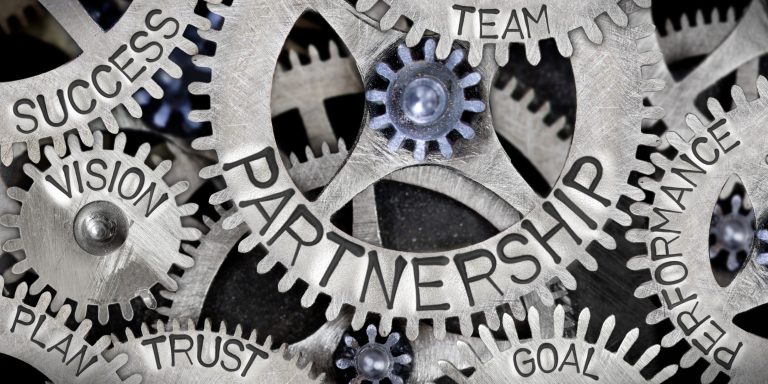 Macro photo of tooth wheel mechanism with Partnership related words imprinted on metal surface.