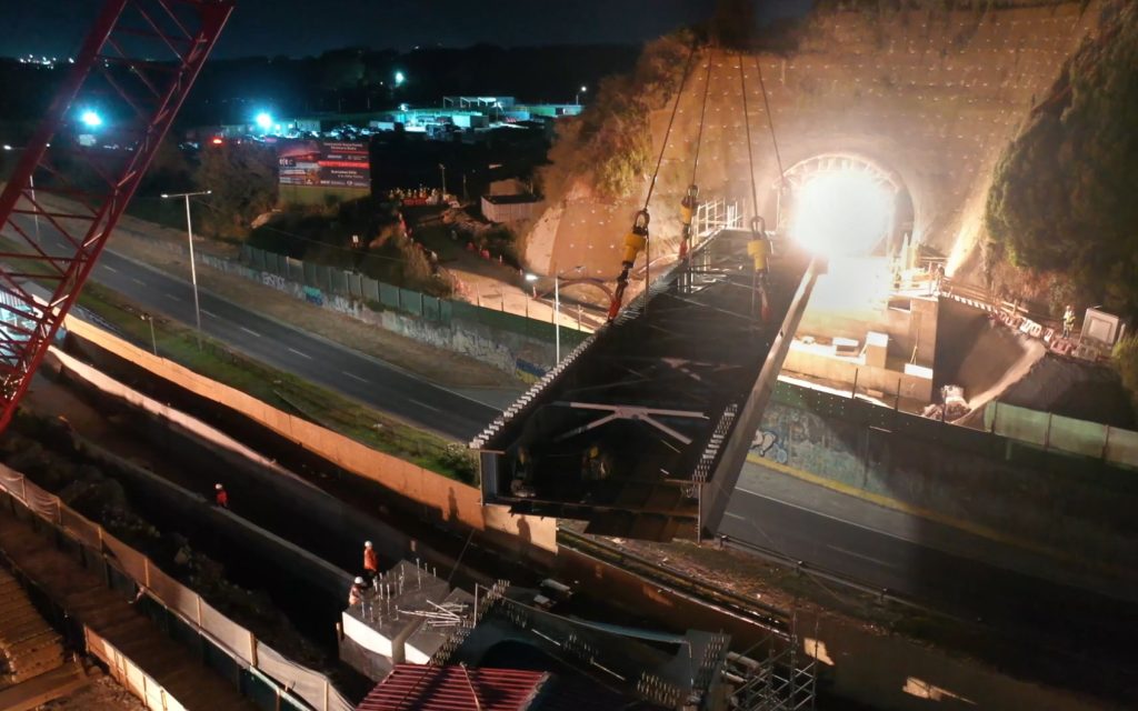 Engineered Rigging's SynchHoist is pictured leveling the load of an assymetrical bridge beam into position above the Biobio River in Chile, South America, at night.