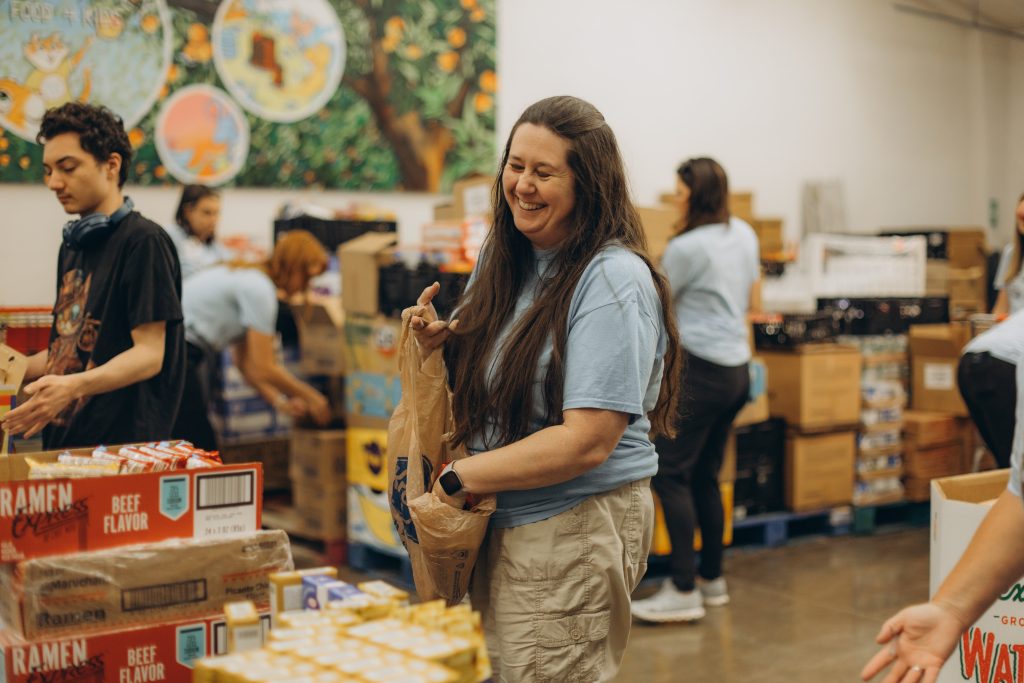 RVF4K volunteer shown pack summer meals for children in 2025, with a big smile.